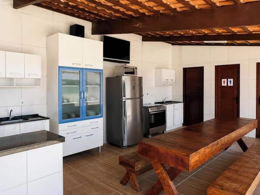 A kitchen with white cabinets, a blue refrigerator, a wooden dining table, and a tiled floor.