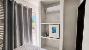 Un baño con ducha, inodoro, lavamanos y ventana con cortinas.