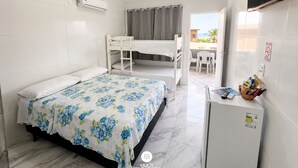 Ett hotellrum med en våningssäng, ett skrivbord med en stol, ett kylskåp och en luftkonditioneringsanläggning.