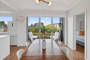 Una cocina moderna con una mesa y sillas de madera, un comedor con vistas al exterior y un dormitorio acogedor con cama y almohadas.