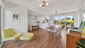 A spacious living area with a wooden floor, a dining table, and a kitchen in the background. - Seventy at Yellow Doors (Goolwa South)