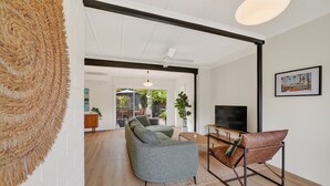 A modern living room with a sofa, armchair, and TV. - Seventy at Yellow Doors (Goolwa South)