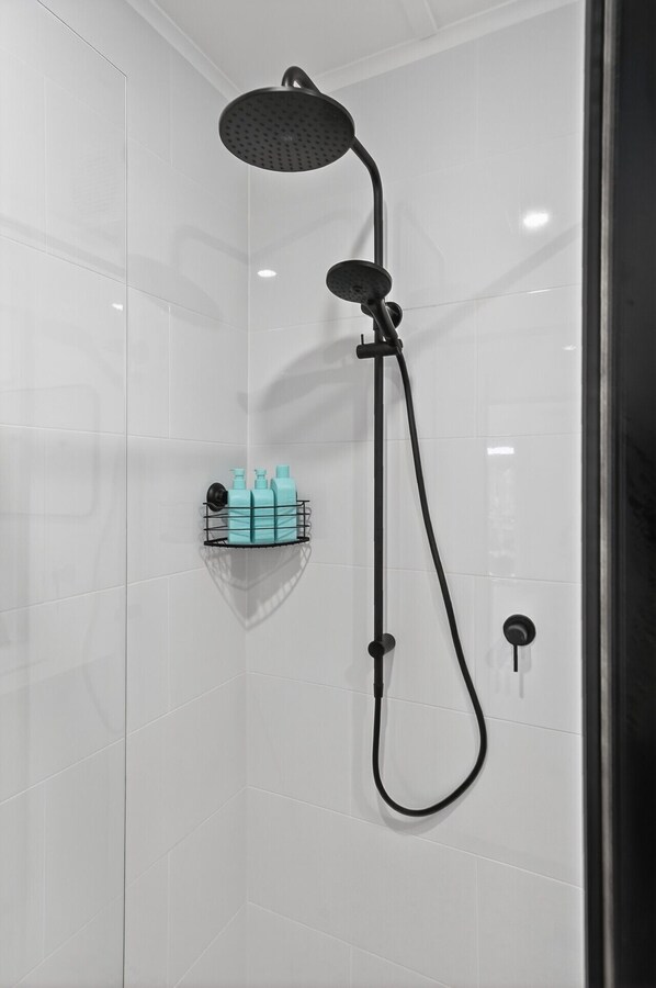 Un box de ducha moderno con un cabezal de ducha de mano y un cabezal de ducha tipo lluvia.
