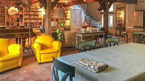 Een knus vertrek met een bed, een eettafel, stoelen, een boekenkast en een trap.