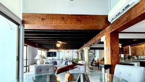 En moderne stue med sofalounge, glasbord og et træloft.