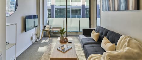 Un salon moderne avec un canapé, une table basse et un téléviseur.