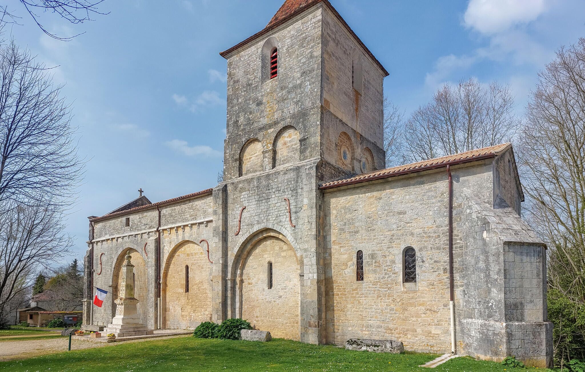 A historic stone church with a bell tower, arched windows, and a flag.