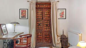 Een kamer met een bed, een bureau, een stoel, een lamp, een radiator en een decoratieve deur.