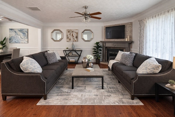 A living room with two sofas, a coffee table, a fireplace, and a television.