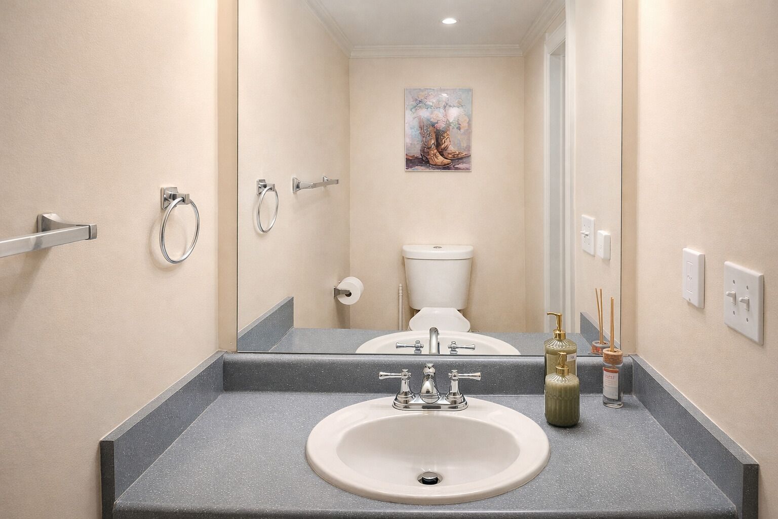 Un bagno con lavandino, WC e uno specchio che riflette l'ambiente.