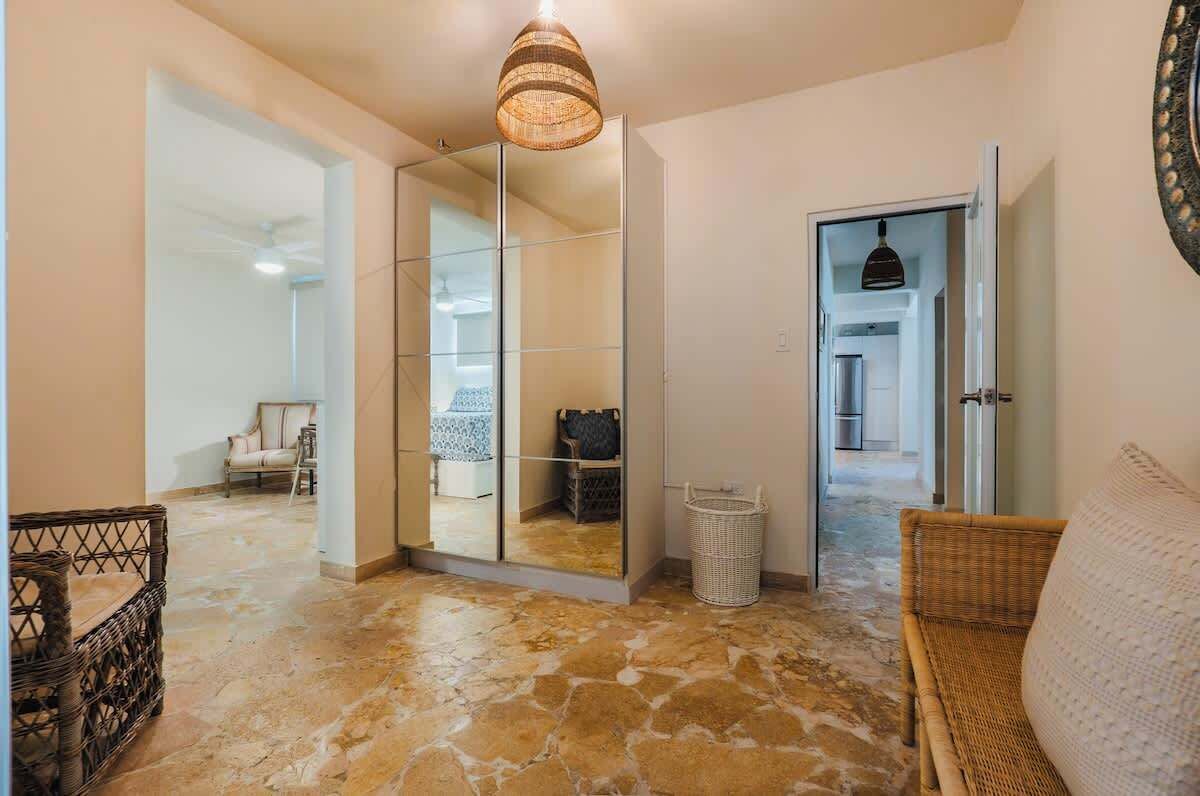 A hallway with a glass partition, wicker furniture, and a tiled floor.