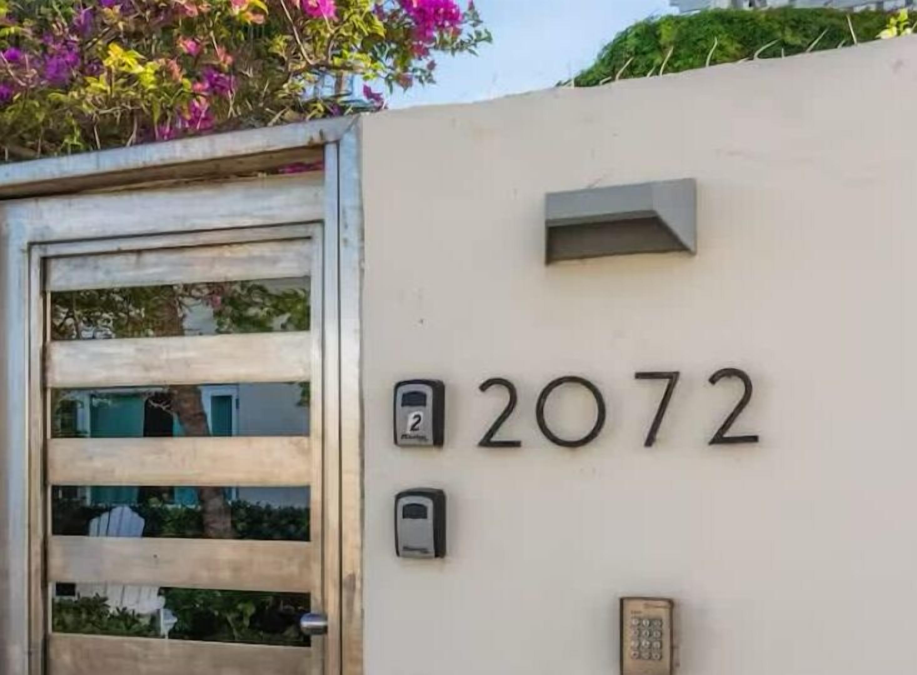 Un bâtiment portant le numéro 2072, une porte avec un panneau de verre et une boîte aux lettres.
