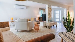 A spacious living room with a sofa set, a coffee table, and a television. - Pelegrina Beach Haus 6BR Chef Powered G SJ (San Juan)