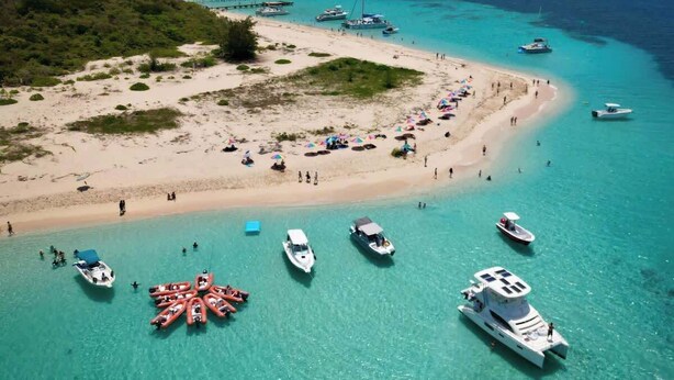 An aerial view of a beach with clear turquoise waters, boats, and people. - Pelegrina Beach Haus 6BR Chef Powered G SJ (San Juan)