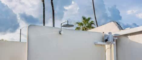Een dakterras met een witte muur, een metalen hekwerk en een klein metalen emmer.