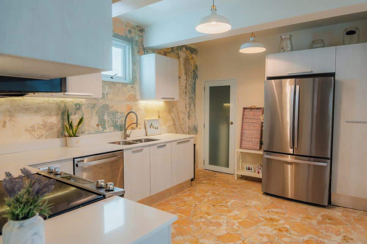 A modern kitchen with white cabinets, a stainless steel refrigerator, and a stone-patterned floor.