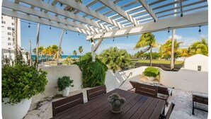 An outdoor patio with a wooden table, benches, and a pergola. - Pelegrina Beach Haus 6BR Chef Powered G SJ (San Juan)