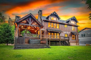 Eine große Blockhütte mit Veranda, zahlreichen Fenstern und einem Steinkamin.