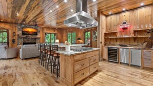 Ein Holzinterieur mit Kücheninsel, Barhocker und Kamin aus Stein.