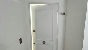 A white door with a number plate, a light switch, and a black and beige floor. - Cozy apartment in front of Torpederas beach, ideal for resting. (Valparaíso)