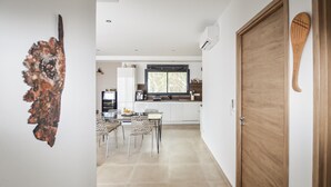 Una cocina moderna con armarios blancos, una ventana y un comedor con sillas.