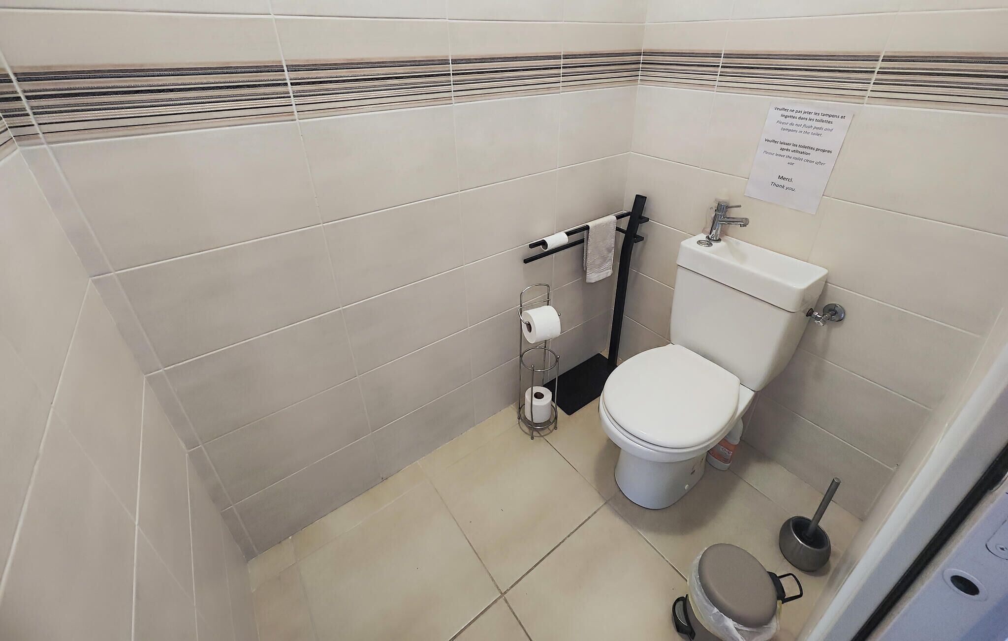 A small, clean bathroom with a toilet, a hand dryer, and a paper towel dispenser.