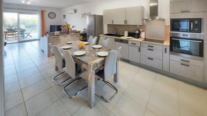 Una cocina moderna con electrodomésticos de acero inoxidable, una mesa de comedor preparada para cuatro personas y vistas al exterior.