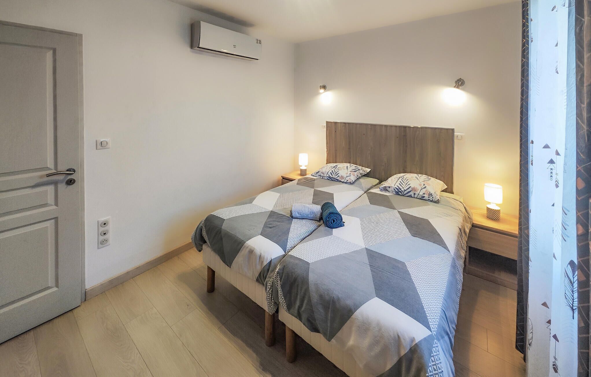 Une chambre à coucher avec un lit, des lampes de chevet, une porte et un appareil de climatisation.