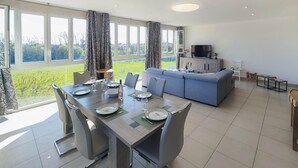 A modern living room with a dining area, large windows, and a flat-screen TV. - Gorgeous apartment in Mirepeisset with WiFi (Mirepeisset)