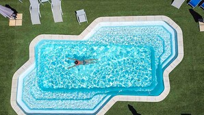 An above-ground swimming pool with a person swimming, surrounded by lawn chairs and umbrellas. - Gorgeous apartment in Mirepeisset with WiFi (Mirepeisset)