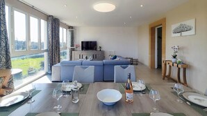 A modern living room with a sofa, dining table set for six, and a television. - Gorgeous apartment in Mirepeisset with WiFi (Mirepeisset)
