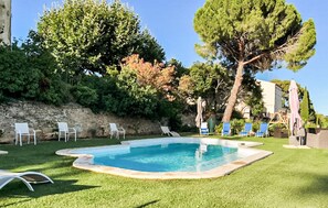 A swimming pool with lounge chairs, a stone wall, and trees. - Gorgeous home in Mirepeisset with outdoor swimming pool (Mirepeisset)