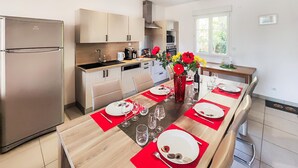 A modern kitchen with a central island, a refrigerator, and a dining area set for a meal. - Gorgeous home in Mirepeisset with outdoor swimming pool (Mirepeisset)