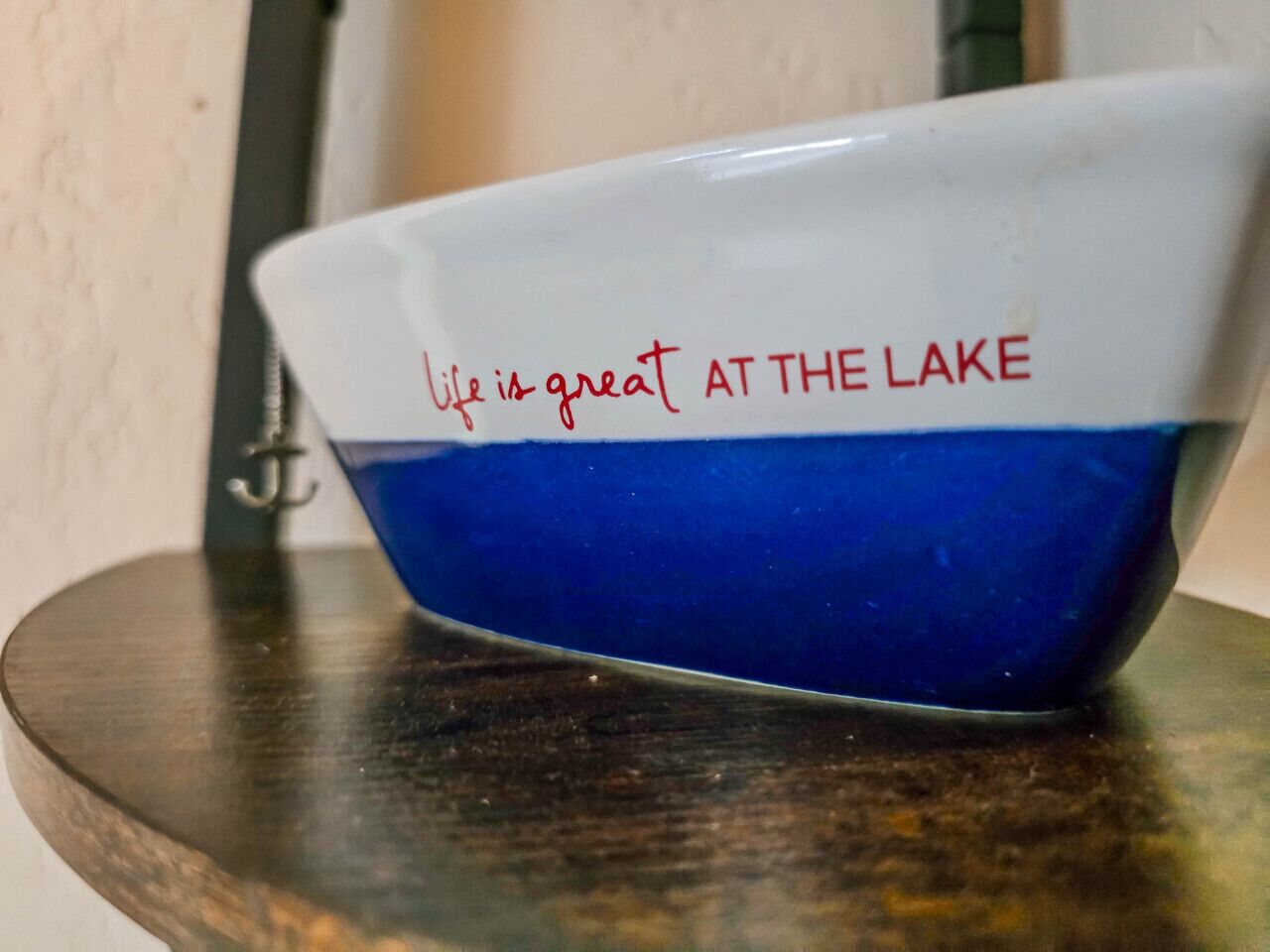 A white and blue bowl with the text 'life is great at the lake' on a wooden surface.