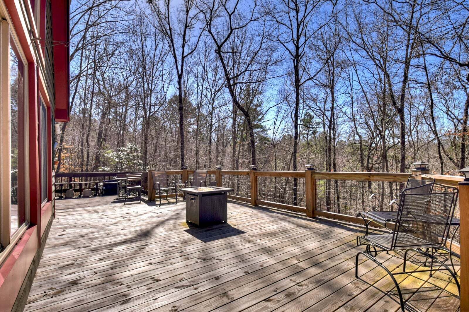 Une terrasse en bois avec des sièges extérieurs, un foyer et une vue sur une forêt.