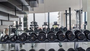Ein Fitnessstudio mit Gewichtshalterungen und Kurzhanteln, modernes Design und großen Fenstern.