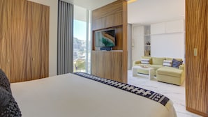 Ein modernes Hotelzimmer mit einem großen Bett, einem Fernseher, einer Couch und Blick auf die Stadt.