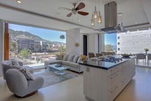 A modern living room with a sofa, coffee table, and a kitchen island with a stove. - Park Condo Zona Romántica, Terrace+ Infinity Pool (Puerto Vallarta)
