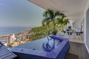 Ein Balkon mit Whirlpool, Sitzgelegenheit im Freien und Blick aufs Meer.