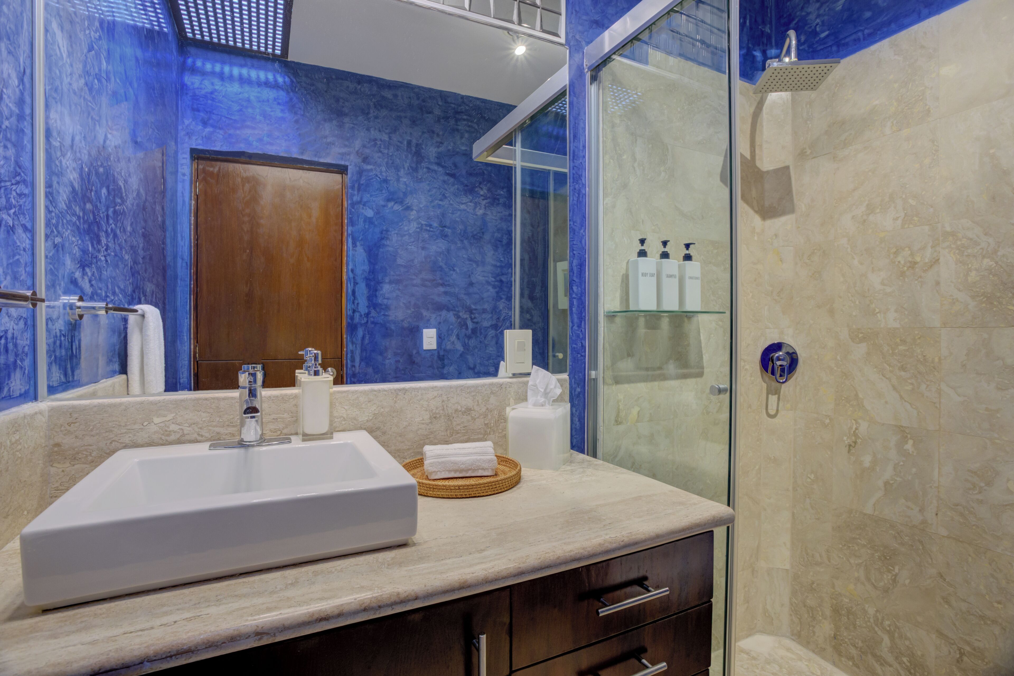 Une salle de bain avec un grand lavabo, une douche en verre et un miroir.