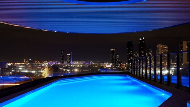 Ein Rooftop-Pool mit Infinity-Kante und Blick auf die nächtliche Skyline.