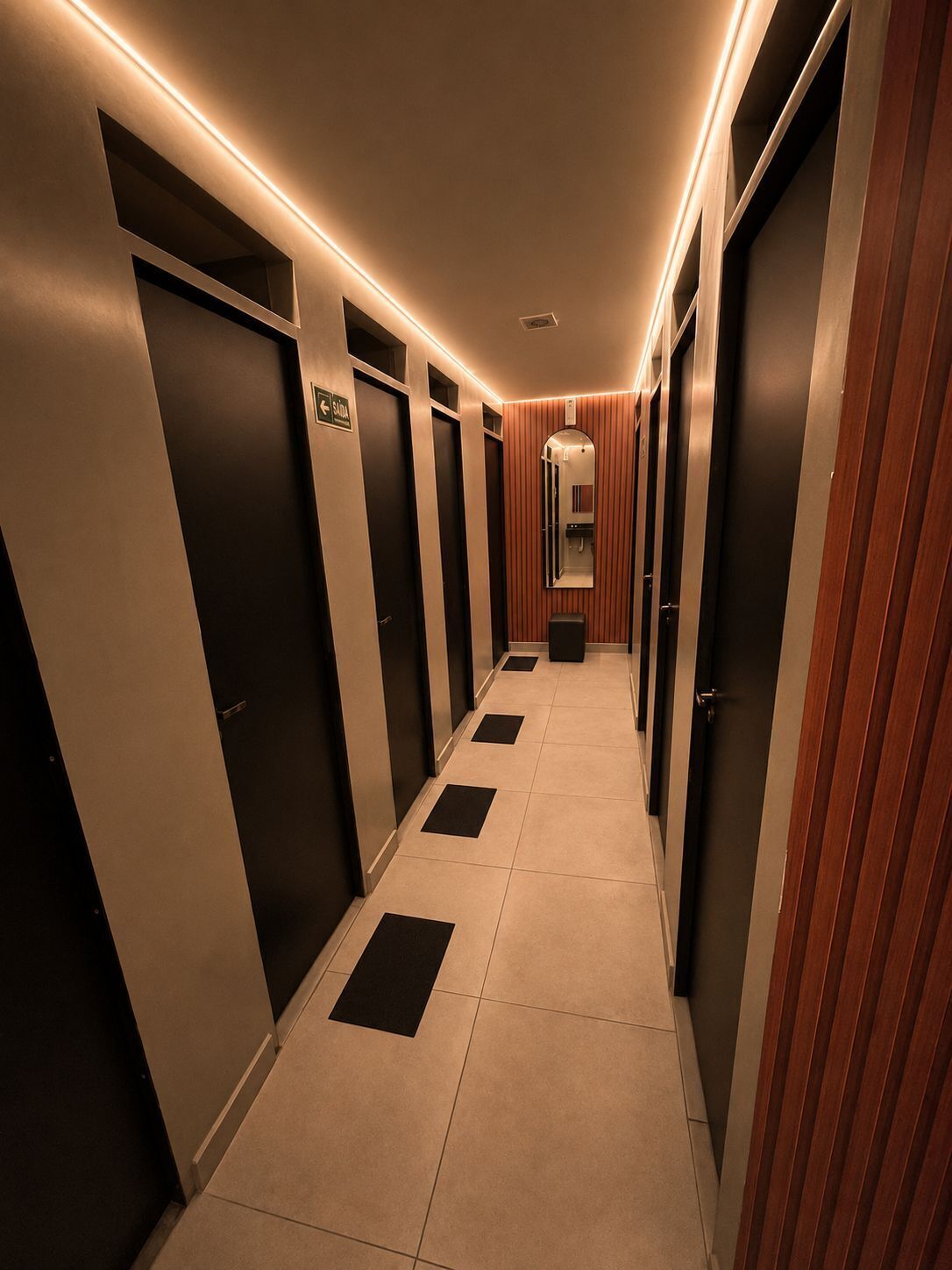 A hallway with doors, a mirror, and a sign indicating the direction to the bathroom.