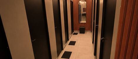 A hallway with doors, a mirror, and a sign indicating the direction to the bathroom.