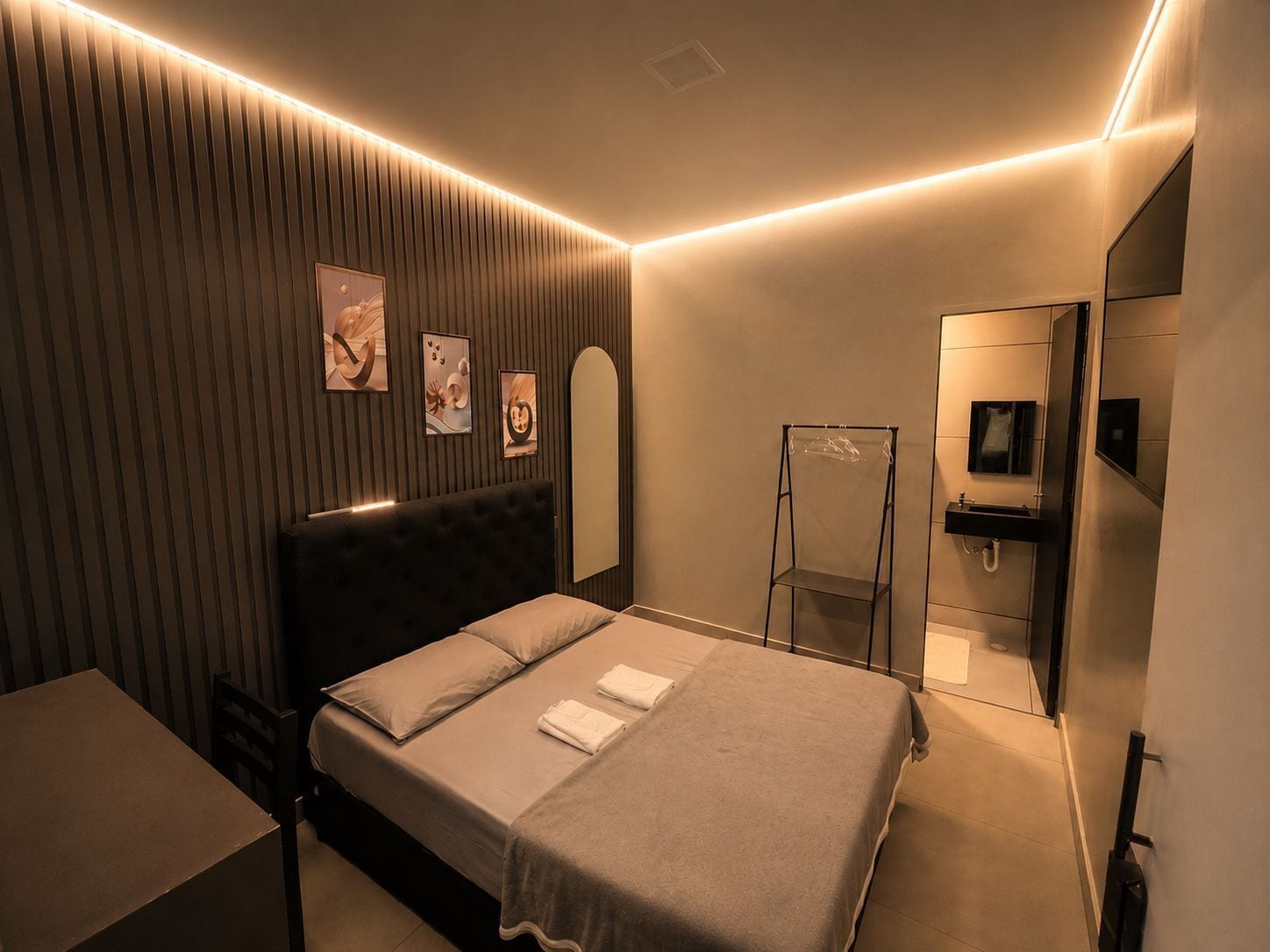 Un dormitorio moderno con cama, mesita de noche y espejo.