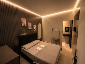Een moderne slaapkamer met een bed, nachtkastje en spiegel.