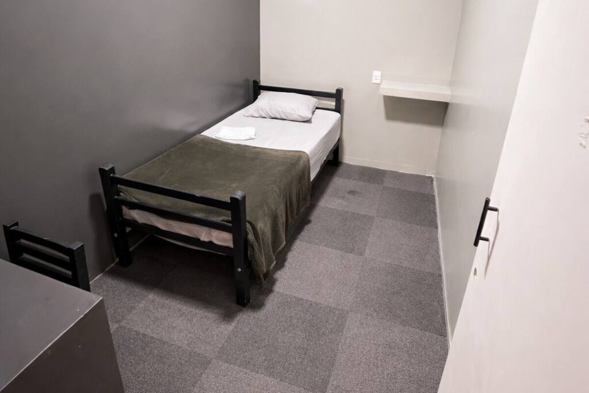 A small, compact room with a single bed, a desk, and a chair.