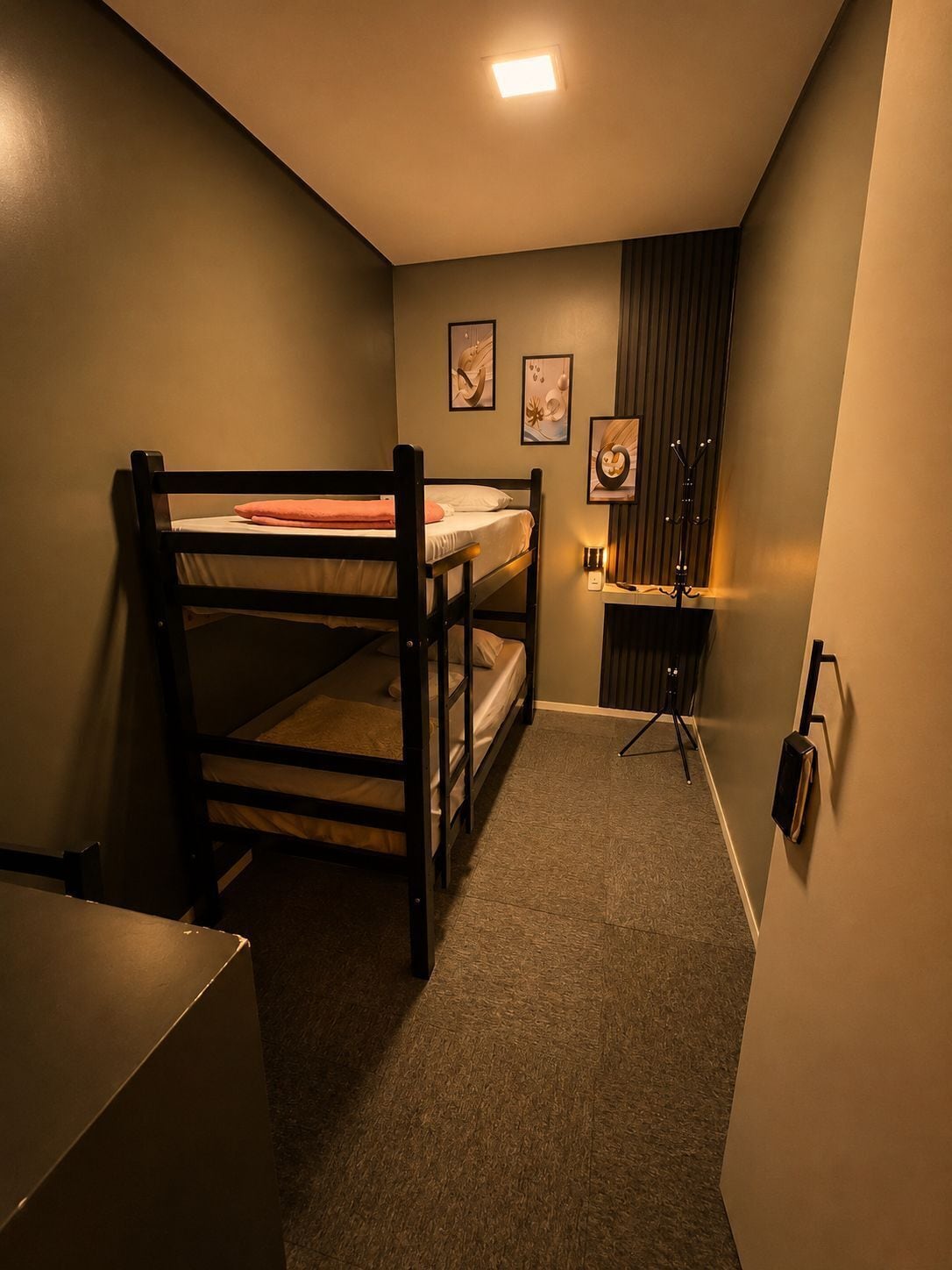 Une chambre avec des lits superposés, un bureau, une chaise et un petit placard.
