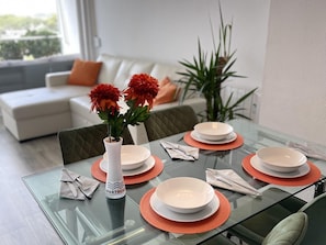 Una mesa de comedor con platos blancos, individuales anaranjados y un jarrón con flores.