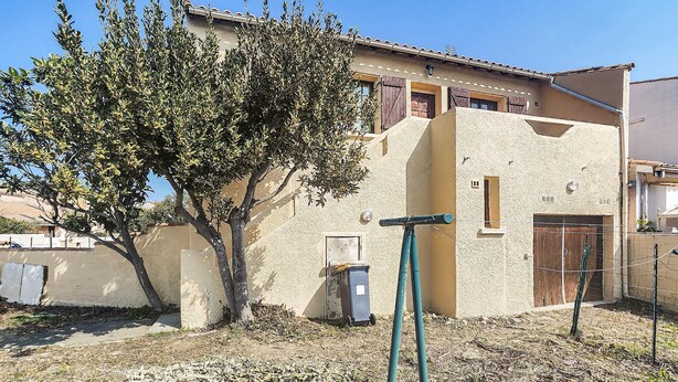 A building with a textured facade, a tree in front, and a clear blue sky. - APPARTEMENT PROCHE PLAGE (Valras-Plage)