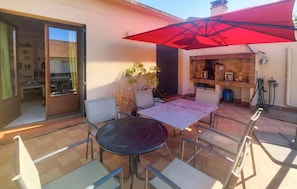 An outdoor patio with a table and chairs, a red umbrella, and a kitchen area with a chimney. - 4 bedroom stunning home in Béziers (Béziers)